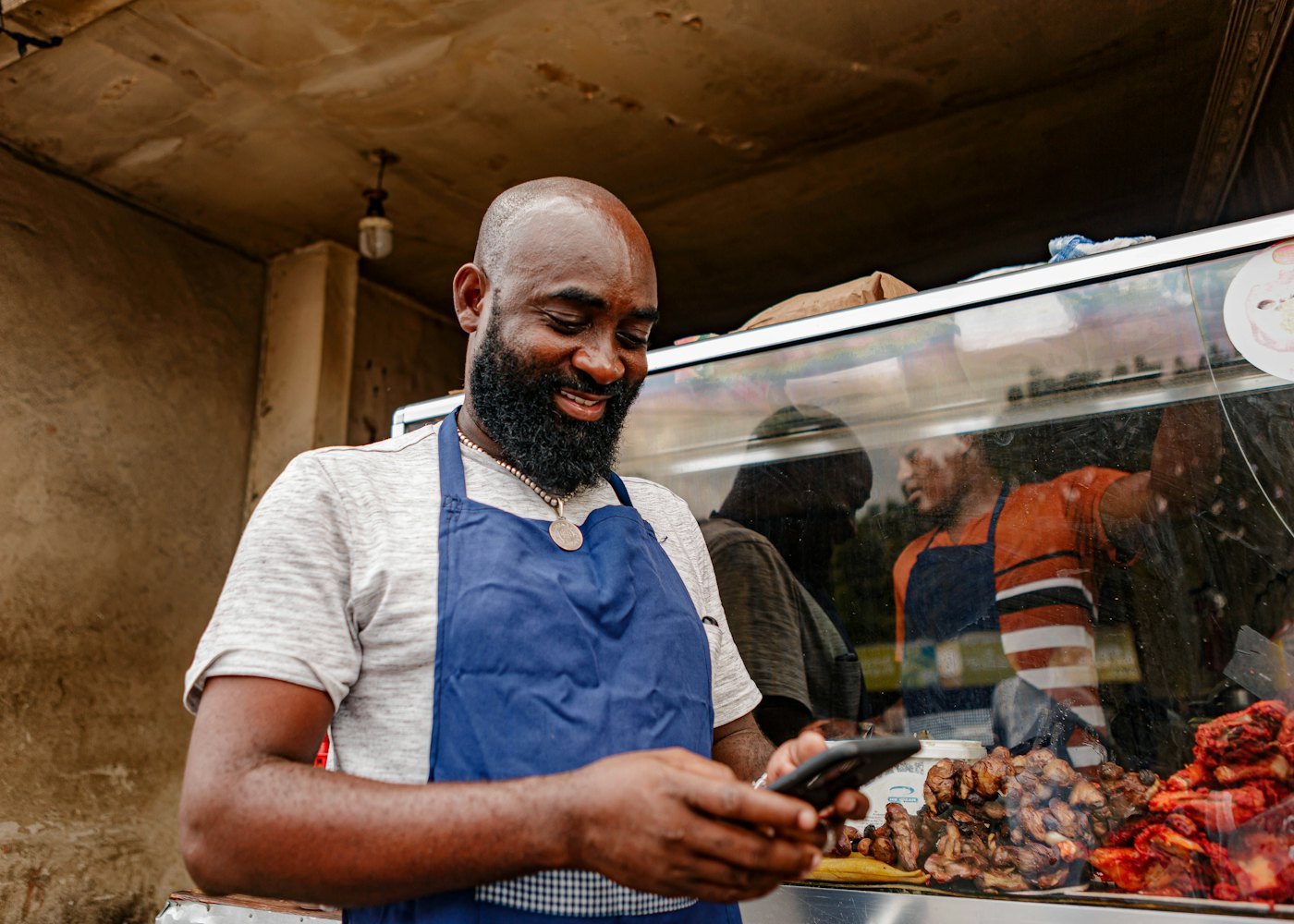 Un commerçant regarde son téléphone derrière son comptoir.
